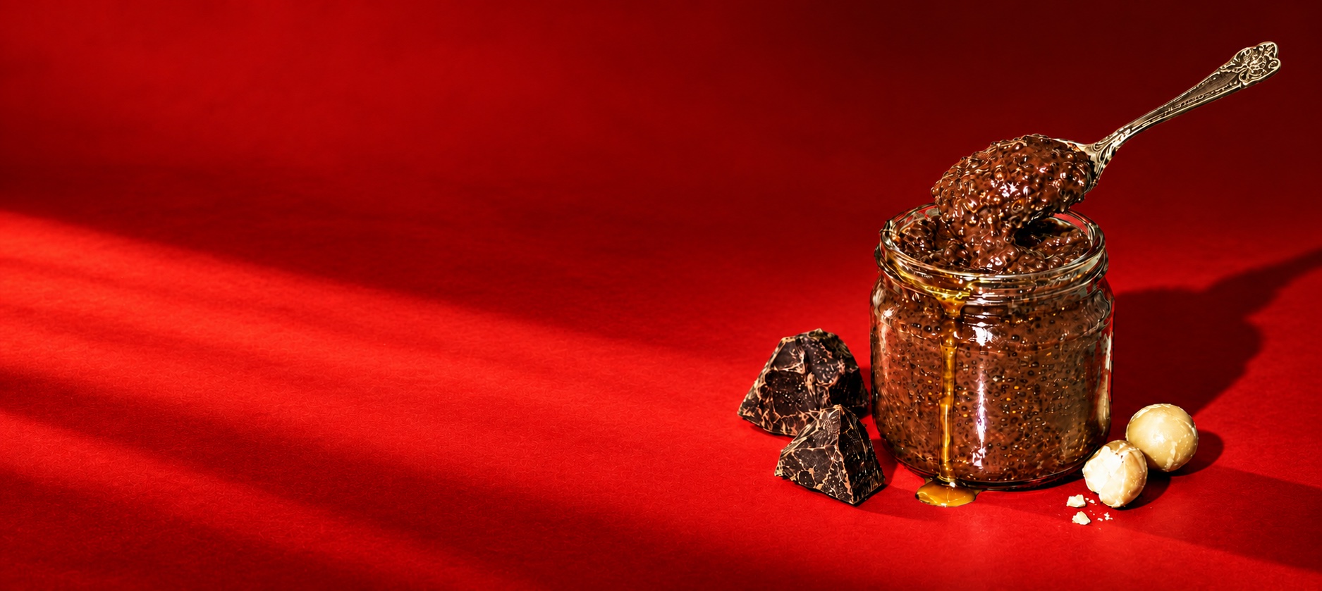 the chia pudding jar, the spoon, cacao and macadamias on the lit red.
